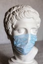 The head of an antique sculpture in a medical face mask. Coronavirus pandemic concept Royalty Free Stock Photo