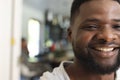 Head of appy african american man with beard standing and smiling in sunny house