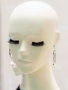 Head of a bald white female mannequin with false eyelashes and silver earrings Royalty Free Stock Photo