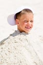 Head of a boy in cap buried in the sand Royalty Free Stock Photo