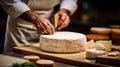 A head of brie cheese in man\'s cheesemaker hands. delicious dairy products. cheese camembert on wooden plank