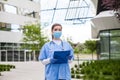 Head of care wearing personal protective equipment holding folder standing in front of nursing home,Coronavirus COVID-19 pandemic