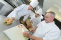 head-chef and apprentices preparing dish in kitchen Royalty Free Stock Photo