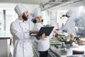 Head chef with modern laptop showing gourmet dish recipe to sous chef required for gastronomic event held at restaurant. Royalty Free Stock Photo