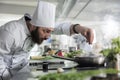 Head chef seasoning gourmet dish in pan while cooking fine dining food served at dinner service in restaurant. Royalty Free Stock Photo