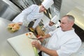 Head-chef teaching colleagues how to slice vegetables