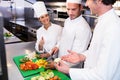 Head chef teaching his colleagues how to slice vegetables