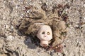 Head of children's doll on the beach trash