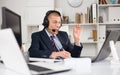 Head of the company conducts online negotiations with business partners in headphones