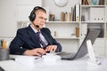 Head of the company conducts online negotiations with business partners in headphones