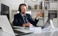 Head of the company conducts online negotiations with business partners in headphones