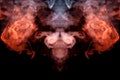 The head of a ghost on a black background from a smoke pattern of an orange-colored vape vaporizing Royalty Free Stock Photo