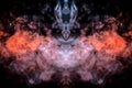 The head of a ghost on a black background from a smoke pattern of an orange-colored vape vaporizing like flame Royalty Free Stock Photo