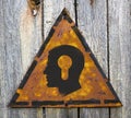Head with a Keyhole Icon on Rusty Warning Sign.