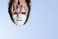 Head of a man in a white mask under the ceiling. Men`s hands hold a flying face. Surrealistic picture of the soul. The concept of