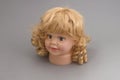 The head of a mannequin of a little girl with golden curls on a gray background.Shop concept, sale, design. Fashionable silicone Royalty Free Stock Photo