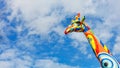 Head and neck of a stylized multi-colored giraffe against a blue, slightly cloudy sky