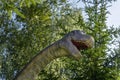 Head and neck of a toy scary dinosaur with an open mouth on a forest background, bottom up view Royalty Free Stock Photo