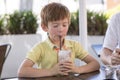 Head portrait of lovely and sweet young kid 7 or 8 years old in yellow shirt enjoying happy drinking ice cream smoothie milk shak