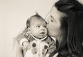 Head portrait of mom kissing her newborn with love