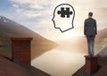 Head with puzzle piece icon and Businessman standing on Roofs with chimney and lake mountain landsca