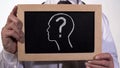 Head with questionmark drawn on blackboard in physician hands, diagnostics