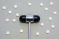 Head of reflex hammer is on gray background surrounded by pills or tablets with ornament of polka dots. Concept photo diagnosis, t