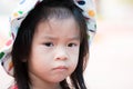 Head short. Upset Asian little girl wear hat pattern polka dot colorful. Candid unhappy child. Kid frowned.