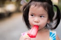 Head shot adorable Asian little child girl eating red ice cream. Kid aged 3 years old. Royalty Free Stock Photo