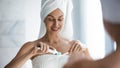 Beautiful woman wearing towel on head applying toothpaste on toothbrush