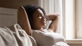 Happy young woman relaxing with closed eyes on sofa. Royalty Free Stock Photo