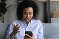 Head shot overjoyed African American woman holding smartphone, reading news