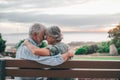 Head shot close up portrait happy grey haired middle aged woman snuggling to smiling older husband, enjoying sitting on bench at Royalty Free Stock Photo