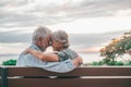 Head shot close up portrait happy grey haired middle aged woman snuggling to smiling older husband, enjoying sitting on bench at Royalty Free Stock Photo