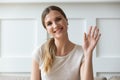 Happy pleasant young woman looking at camera, waving hello.