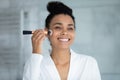 Head shot smiling African American woman using cosmetics brush