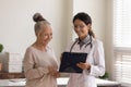 Head shot smiling doctor consulting mature patient, holding clipboard