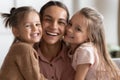 Head shot close up young woman touching cheeks with daughters.