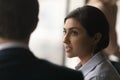 Head shot concentrated millennial indian woman talking to colleague.