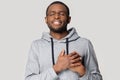 Head shot grateful African American man holding hands on chest