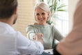 Head shot happy mature businesswoman shaking hands with partners.