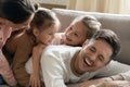 Joyful family of four embracing having fun together on sofa.