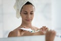 Head shot mirror reflection beautiful woman applying toothpaste on toothbrush