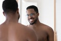 Head shot mirror reflection smiling African American man brushing teeth