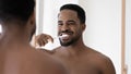 Head shot mirror reflection smiling African American man cleaning teeth