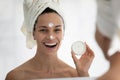 Head shot mirror reflection smiling woman holding face cream jar