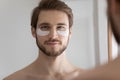 Head shot mirror reflection young man with hydrogel eye patches