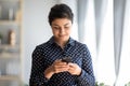 Pleasant millennial indian girl holding smartphone, reading good news sms.