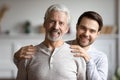 Head shot portrait adult son hugging mature father from back