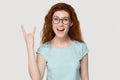 Cheerful redhead millennial woman showing rock and roll hand gesture Royalty Free Stock Photo